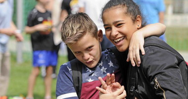 Zwei Jugendliche auf einem Sportplatz lachen in die Kamera