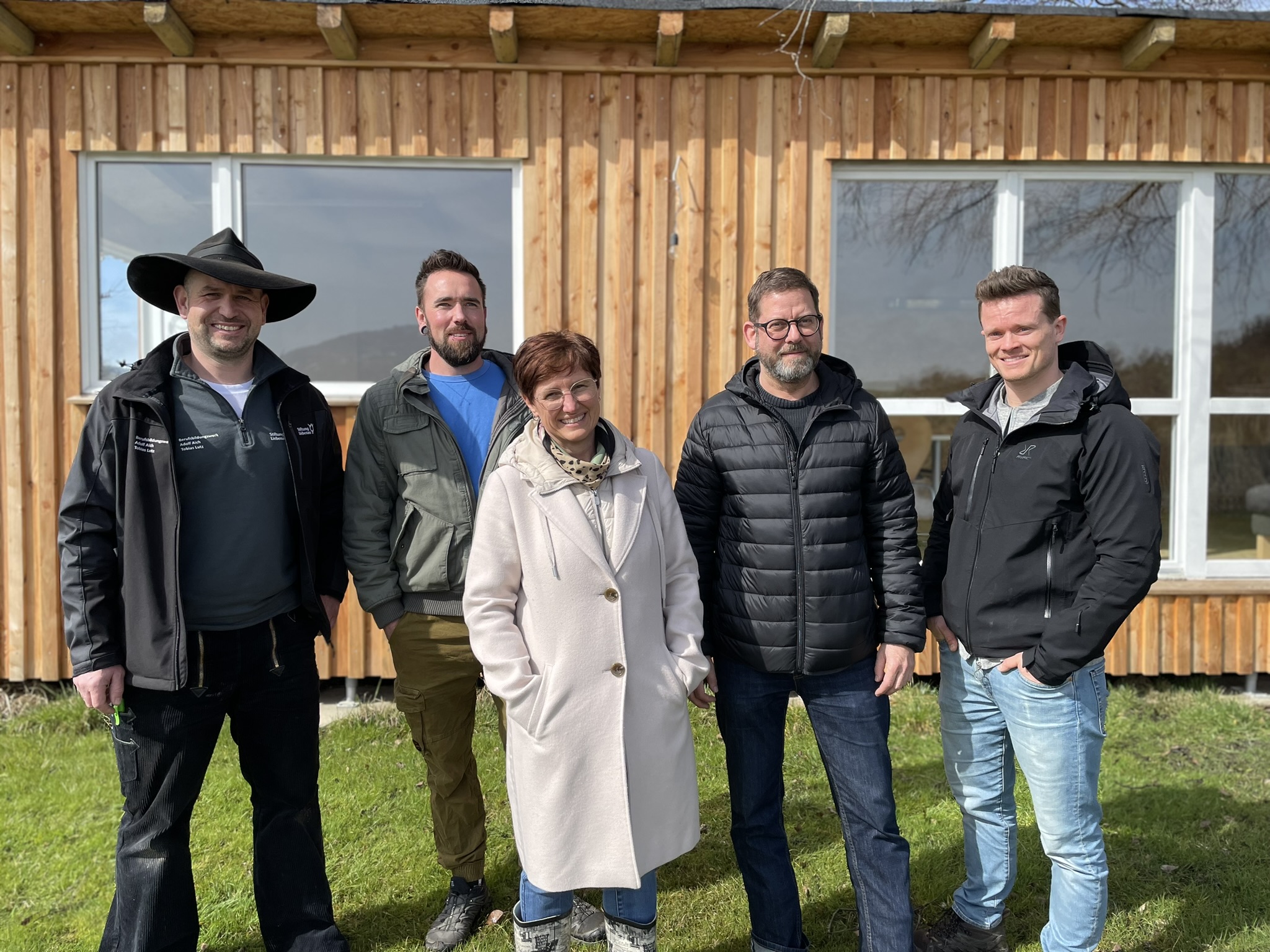 Eine Gruppe von Lehrern, Leitern und die Bürgermeisterin von Wilhelmdorf vor dem Außenklassenzimmer „Beachclub“